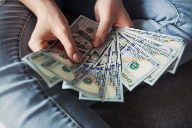 Person holding a fan of US dollar bills. 